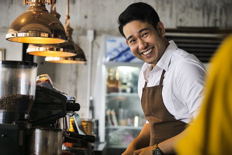 Business Insurance - Smiling Business Owner Helping a Customer at His Coffee Shop