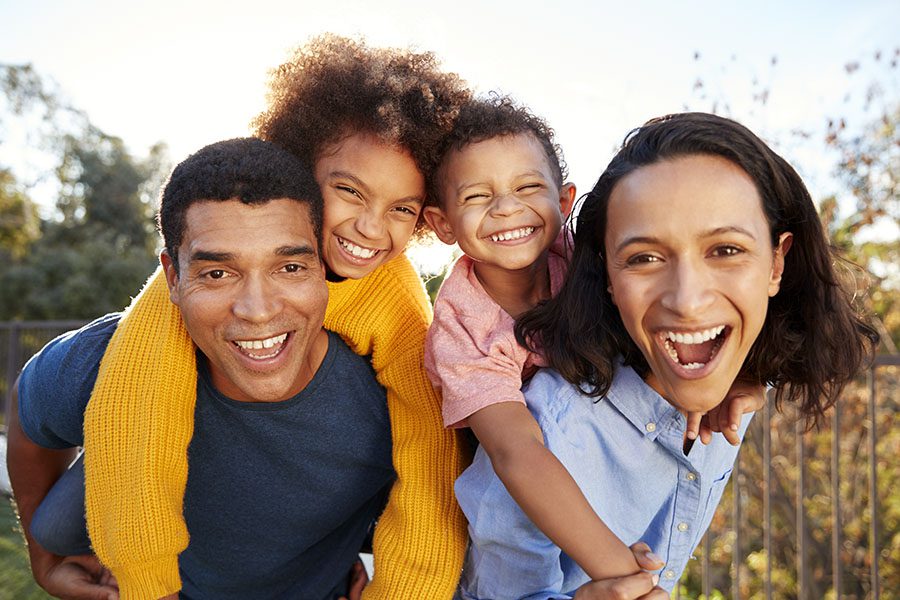 Personal Insurance - Portrait of an Excited Family with Two Kids Standing Outside